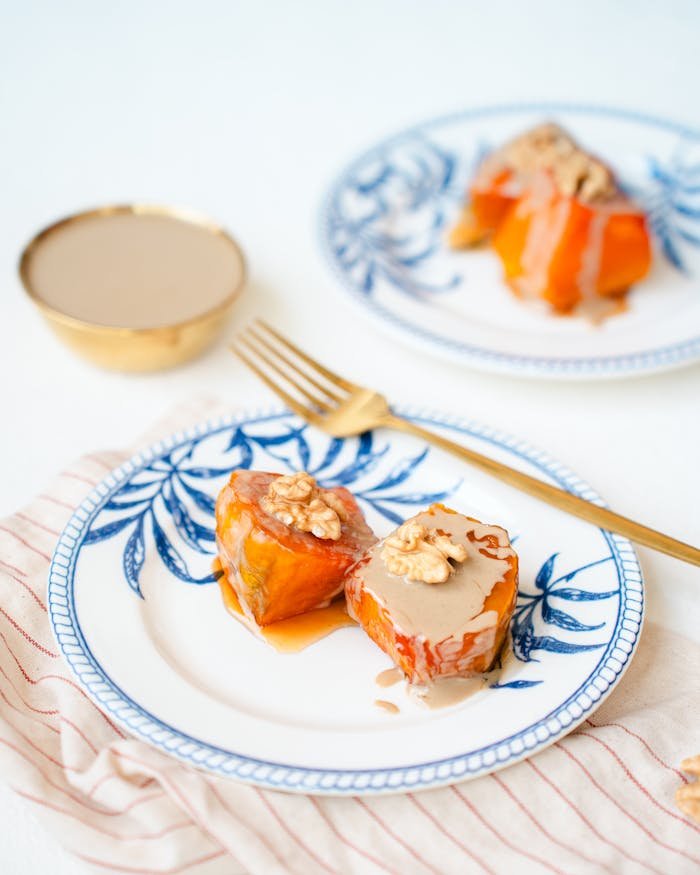 A close-up of a pumpkin dessert topped with walnuts on stylish plates, perfect for a tasty treat.